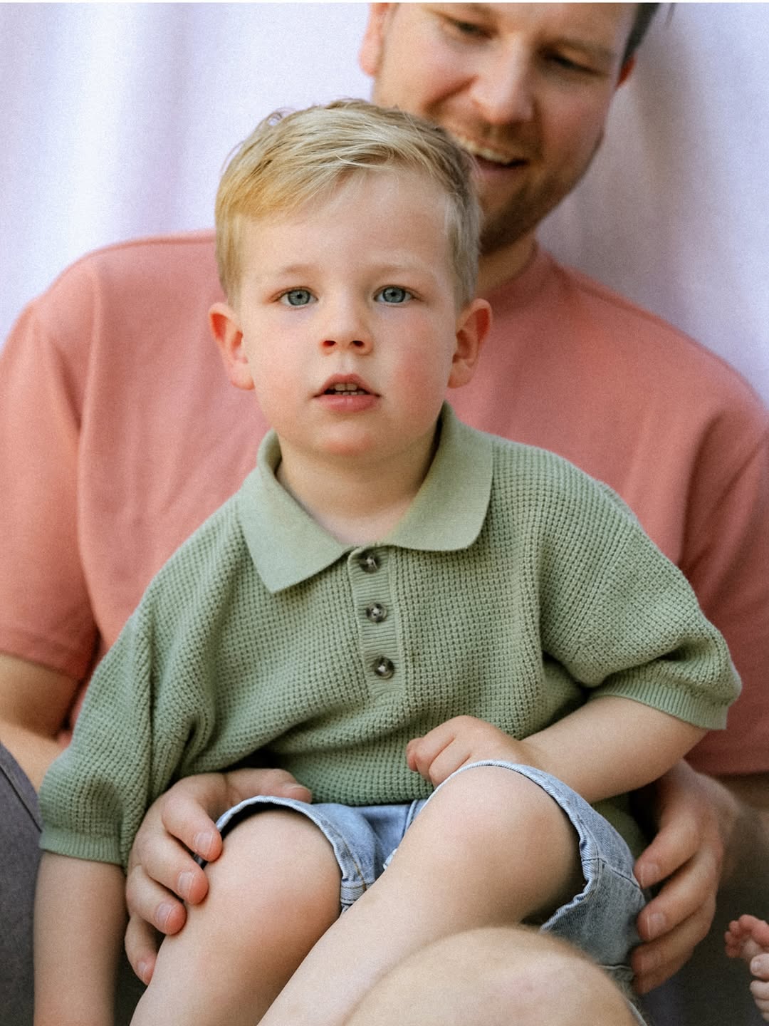 Jongetje in een groene polo op schoot bij zijn vader
