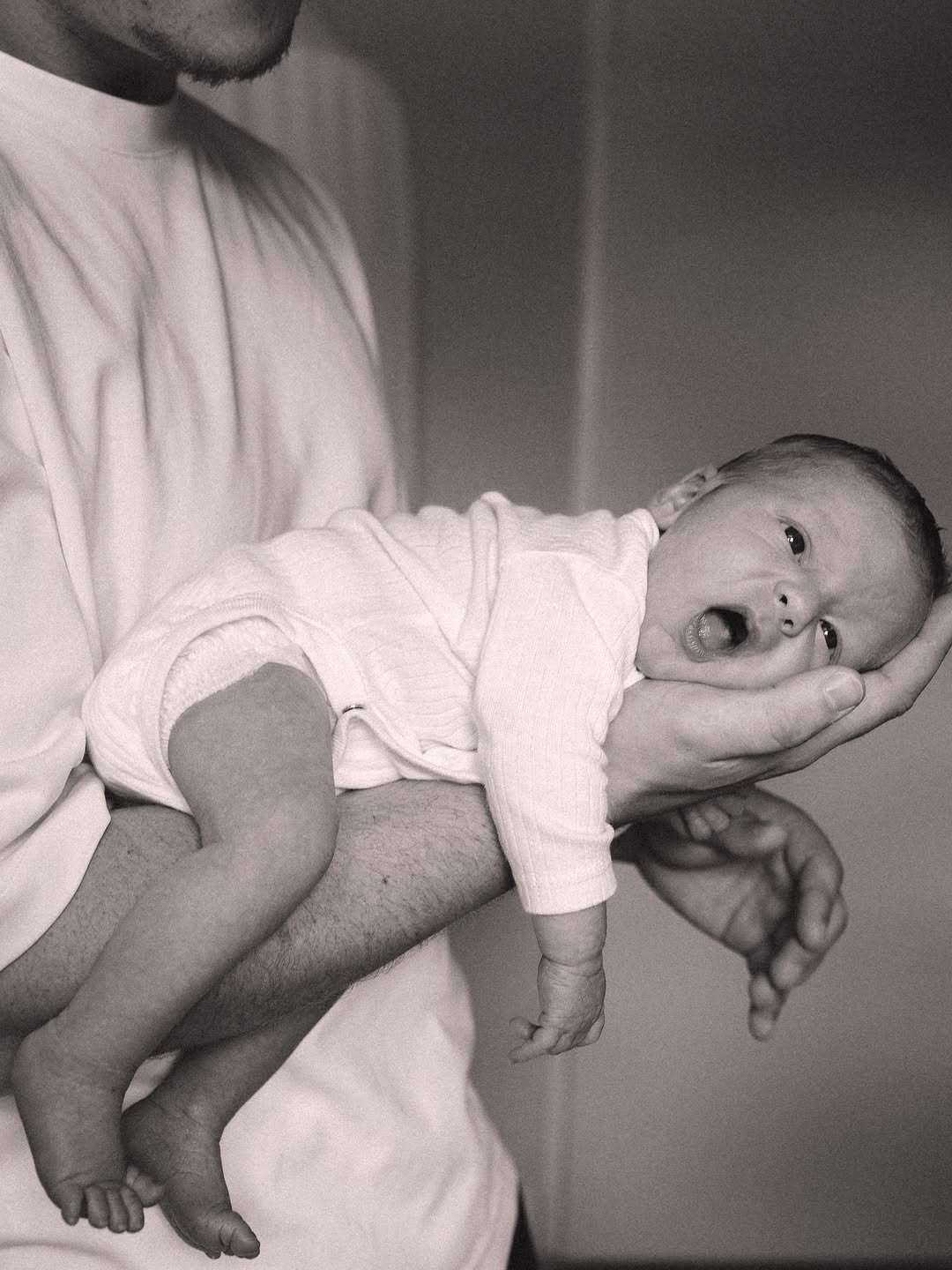 Newborn op de arm van zijn ouder, zwart-wit