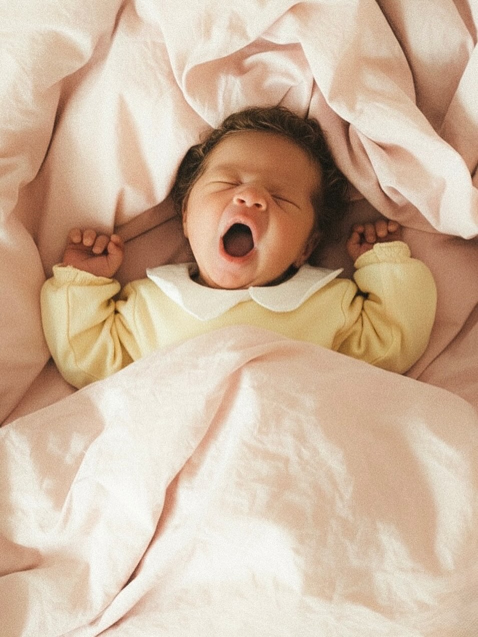 Gapende newborn in een geel pakje