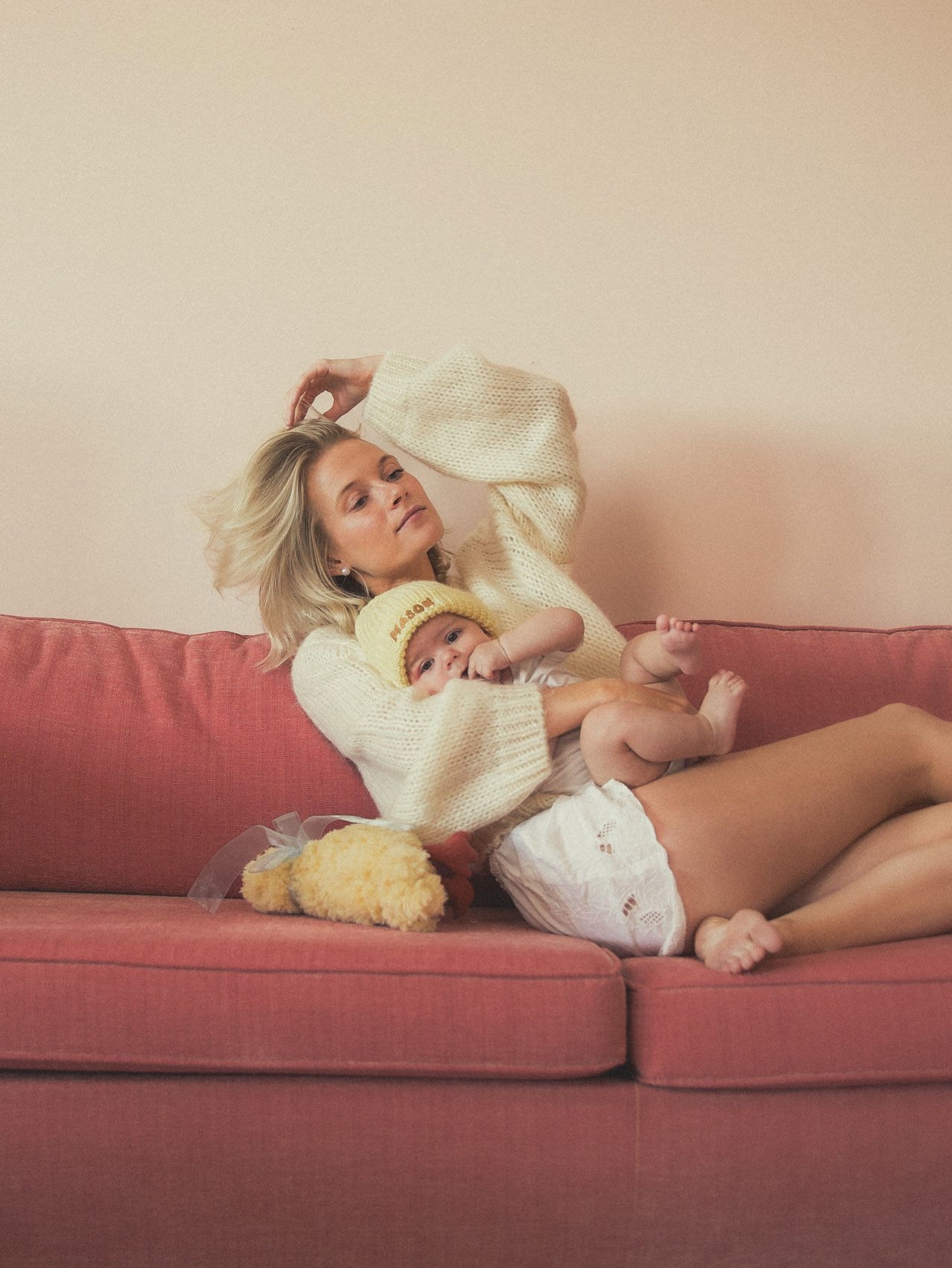 Moeder ligt met haar baby op de roze bank in de studio